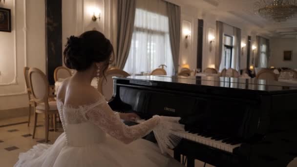 Novia en vestido precioso toca el piano en la sala de cámara lenta — Vídeo de stock
