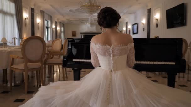 Senhora de vestido branco com pérolas toca piano no salão de casamento — Vídeo de Stock