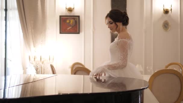 穿着婚纱，裙子蓬松的女人绕着钢琴走着 — 图库视频影像