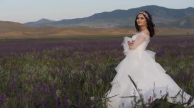 Uzun gelinlikli model, çiçek açan lavantalar arasında poz veriyor.