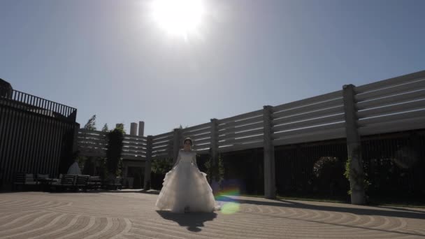 Novia en vestido de novia con paseos de cola a lo largo de patio vacío — Vídeo de stock