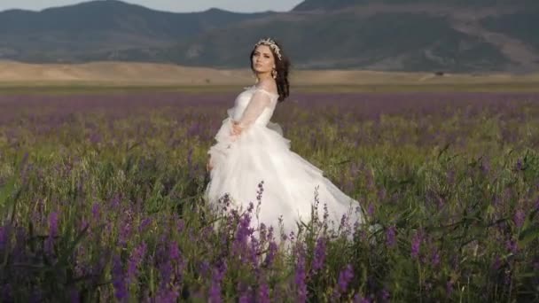Dáma v dlouhých svatebních šatech s bujnou sukní mezi květy — Stock video