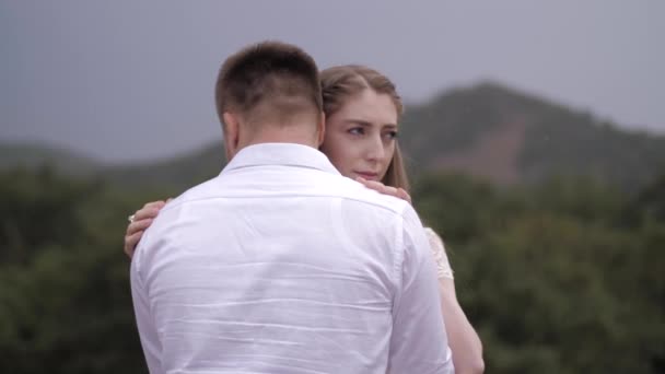 Pretty bride hugs muscular fiance against blurry hills — 비디오