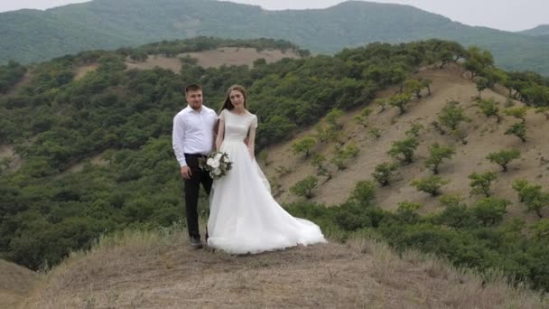 Ragazzo in camicia bianca abbraccia sposa dai capelli lunghi con mazzo di fiori — Video Stock