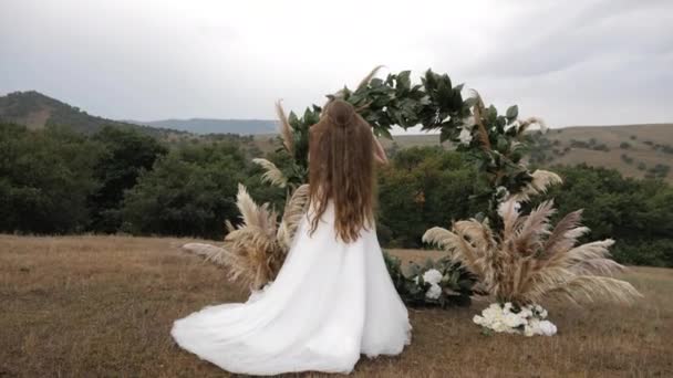 Novia con estilo en vestido blanco largo fija el pelo suelto que fluye — Vídeo de stock