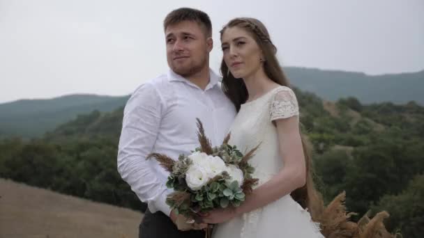 Glückliche Verlobte umarmt langhaarige Braut mit Blumenstrauß — Stockvideo