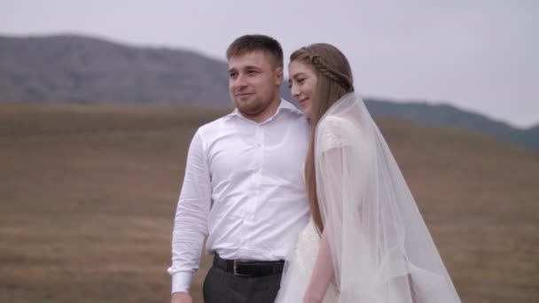 Senhora de cabelos longos em vestido de noiva com véu abraços noivo — Vídeo de Stock
