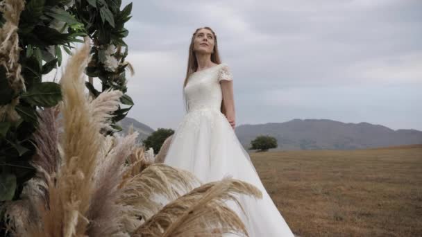 Lady in wedding dress admires cloudy sky standing near arch — 비디오