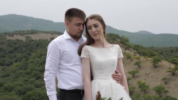 Serious guy hugs happy young woman in long wedding dress — Stock Video