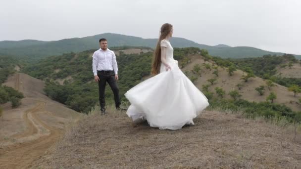 Muscular groom in white shirt looks at elegant bride — Stock Video
