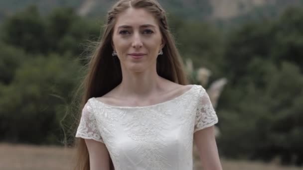jolie brune en robe de mariée longue se dresse contre arche 