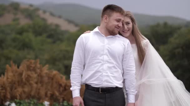 Fashionable wedding couple smiles against forestry hills — ストック動画