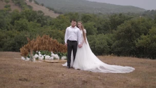 Novia en vestido de novia blanco sostiene muscular mano prometida — Vídeos de Stock
