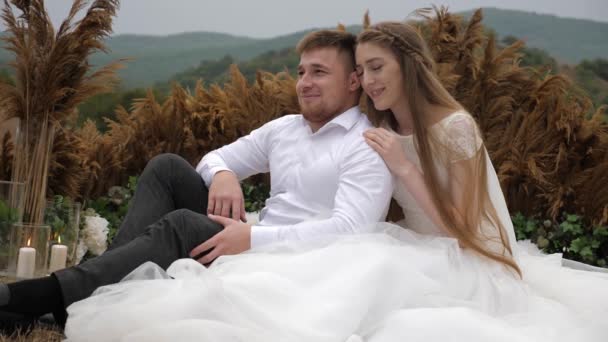 Чудова весільна пара обіймає і позує проти пагорбів — стокове відео