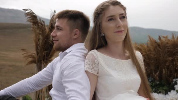 Bride smiles sitting near fiance against hilly landscape — Stock Video