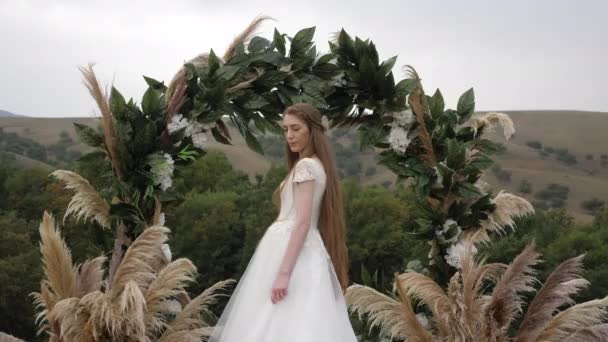 Noiva bonita com longos cabelos soltos fluindo fica perto do arco — Vídeo de Stock