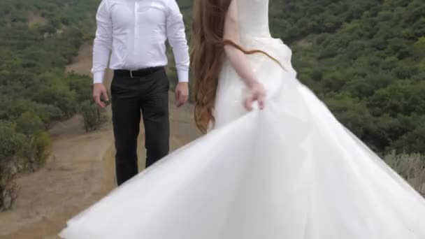 Улыбающийся мужчина смотрит на длинноволосую женщину в свадебном платье — стоковое видео