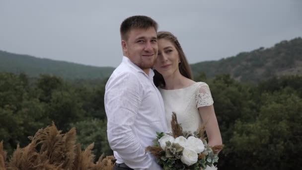 Guy hugs beautiful bride with coloured flower bouquet — 비디오