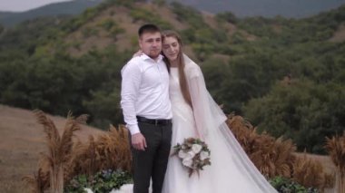 Düğün çifti sarılması ve zarif dekorasyonların yanında gülümsemesi.