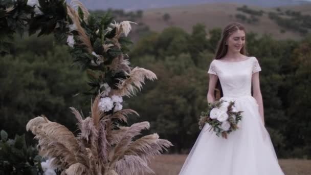 Young woman in dress stands near venue arch with decorations — 비디오