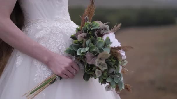 Lady holds bouquet with flowers and leaves at wedding dress — Stock Video