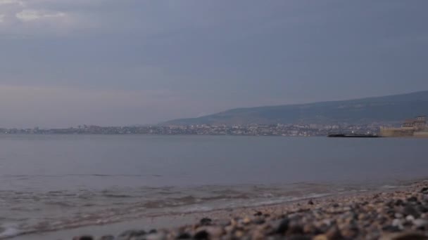 Vagues océaniques roulent sur des rochers avec de la mousse blanche contre la ville — Video