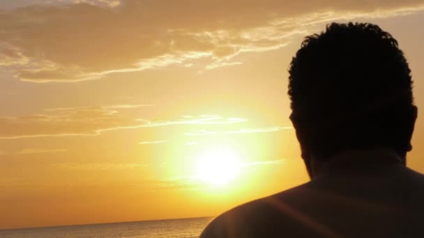 Ragazzo silhouette si siede contro il tramonto tra le nuvole sole — Video Stock