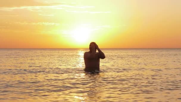 Muž běží ruce na vlasy po potápění stojící v oceánské vodě — Stock video