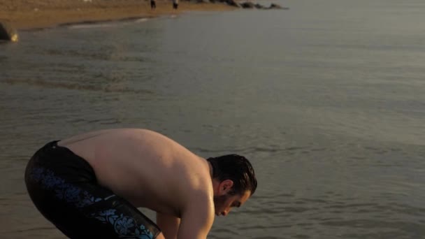 髭を生やした男が穏やかな海の浅瀬に立って頭を洗い — ストック動画