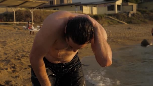 Hombre deportivo con el pelo negro y la barba se para en el agua del océano — Vídeos de Stock