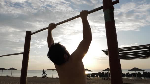 Atlético chico ejercicios pull-ups en arena playa cámara lenta — Vídeos de Stock