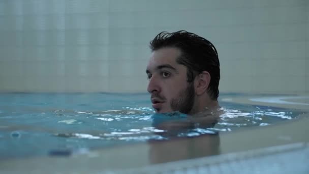 Koncentrovaný plavec s černými vlasy a vousy leží na vodě — Stock video