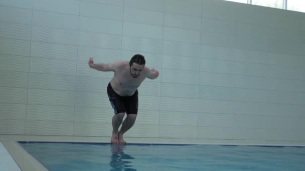 Профессиональный спортсмен с черными волосами и бородой ныряет в бассейн — стоковое видео