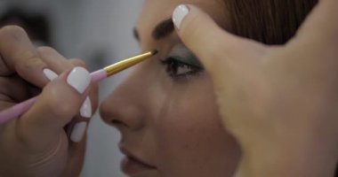 Beyaz manikürlü usta güzel bayan göz farlarını hizalıyor.