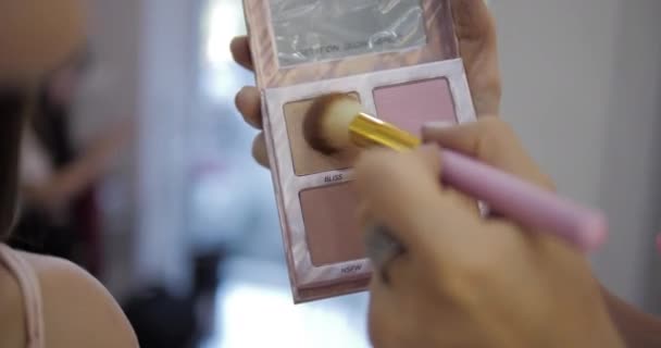 Σαλόνι ομορφιάς εργαζόμενος εφαρμόζει blusher σε ελκυστικό πρόσωπο μοντέλο — Αρχείο Βίντεο