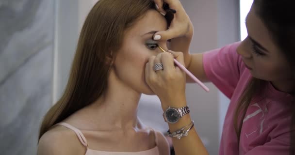 Artista de maquillaje profesional dibuja flechas en las cejas morenas — Vídeo de stock