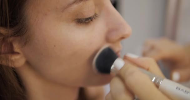 Artista de maquillaje aplica colorete en la cara modelo chica bonita — Vídeos de Stock