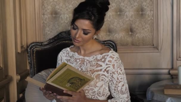 Приваблива брюнетка з модною зачіскою читає книгу — стокове відео