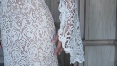 young woman in wedding dress raises hand with lacy sleeve