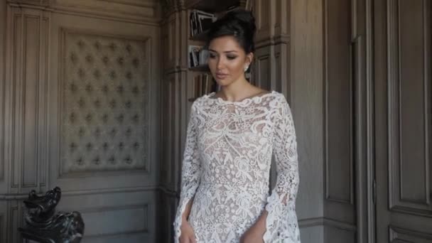 Привлекательная дама в длинном белом кружевном свадебном платье ходит — стоковое видео