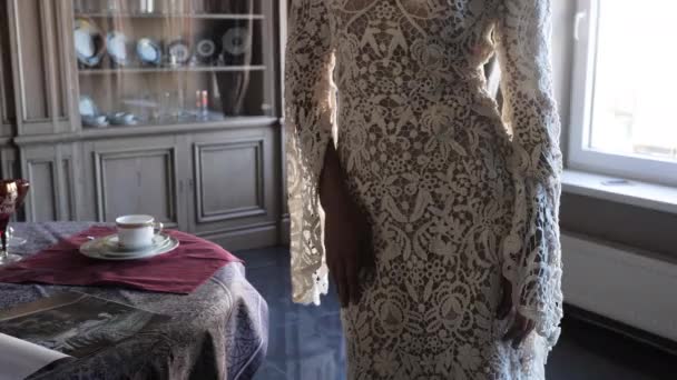 Жінка піднімає півень довгого мережива щільне плаття в кімнаті крупним планом — стокове відео