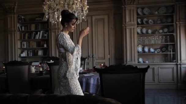 Elegant bride walks about room running hand on large sofa — Stockvideo