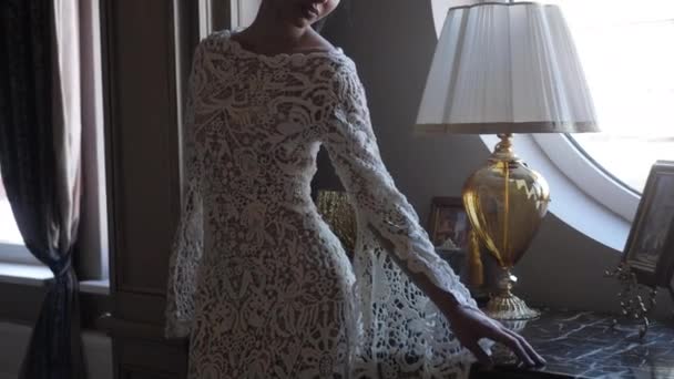 Young woman in long lacy tight dress poses standing at table — Stock videók