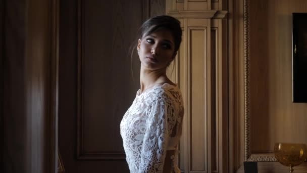 Elegant bride in white lacy wedding dress poses in shadow — Stock video