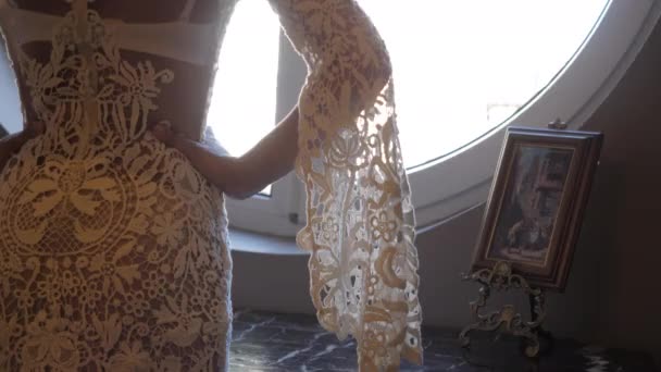 Стройная девушка в платье с длинными кружевными рукавами стоит за столом — стоковое видео