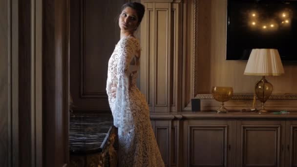 Attractive lady in white dress stands near table and poses — Αρχείο Βίντεο