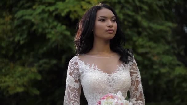 Attraktive afroamerikanische Braut hält Blumen im Park — Stockvideo