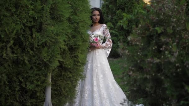 Femme douce en robe de mariée tient bouquet dans le parc vert — Video