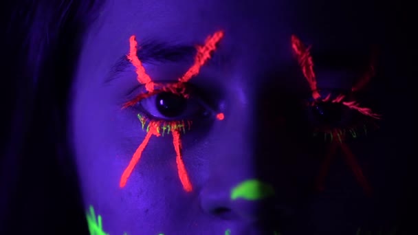 Молодая женщина глаз с оранжево-зеленой тушью и большой крест — стоковое видео