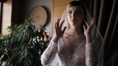 bride in wedding dress with Swarovski crystals touches veil